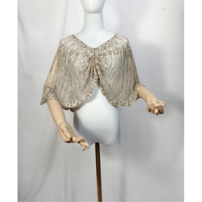 Beige and gold open-knit lace capelet shawl with tie front closure displayed on white mannequin with wooden arms