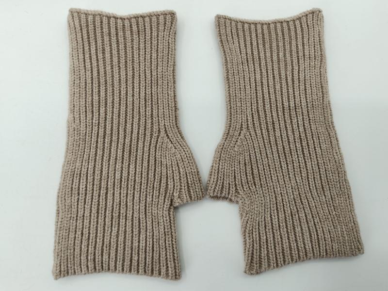 Pair of beige ribbed knit fingerless gloves laid flat on white background, showing thumb hole detail