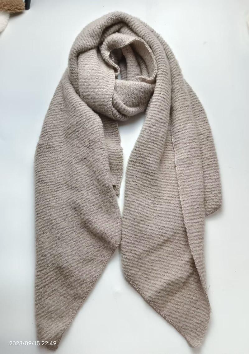 Beige ribbed knit scarf loosely wrapped and laid flat on white surface, showing soft textured stripe pattern