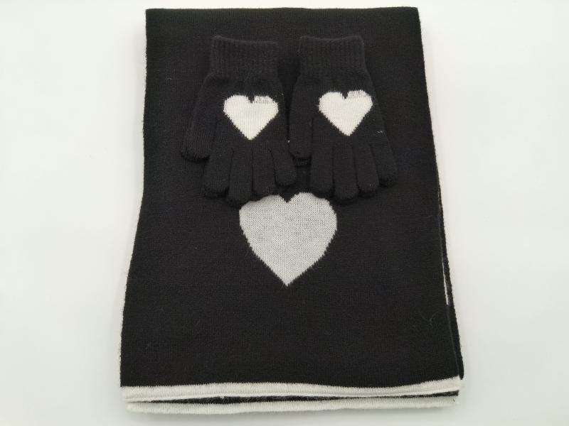 Black knitted scarf and gloves set with white heart intarsia pattern, folded flat on white background