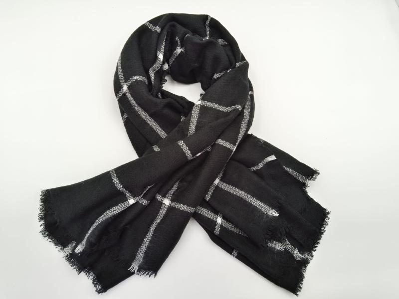 Black woven scarf with white and gray plaid grid pattern, tied in a loose knot, with fringe edges on white background