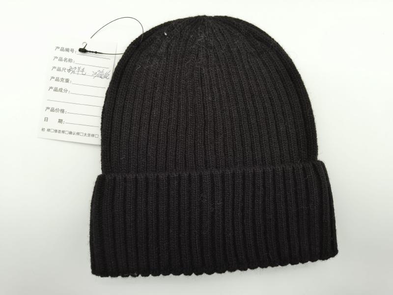 Black chunky ribbed knit beanie hat with folded cuff brim and product tag, flat lay on white background
