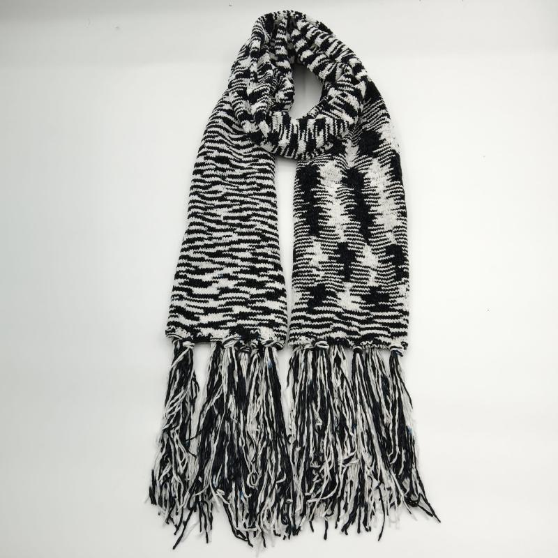 Black and white chunky knit scarf with zebra stripe pattern, bold graphic design, and long tassel fringe ends laid flat