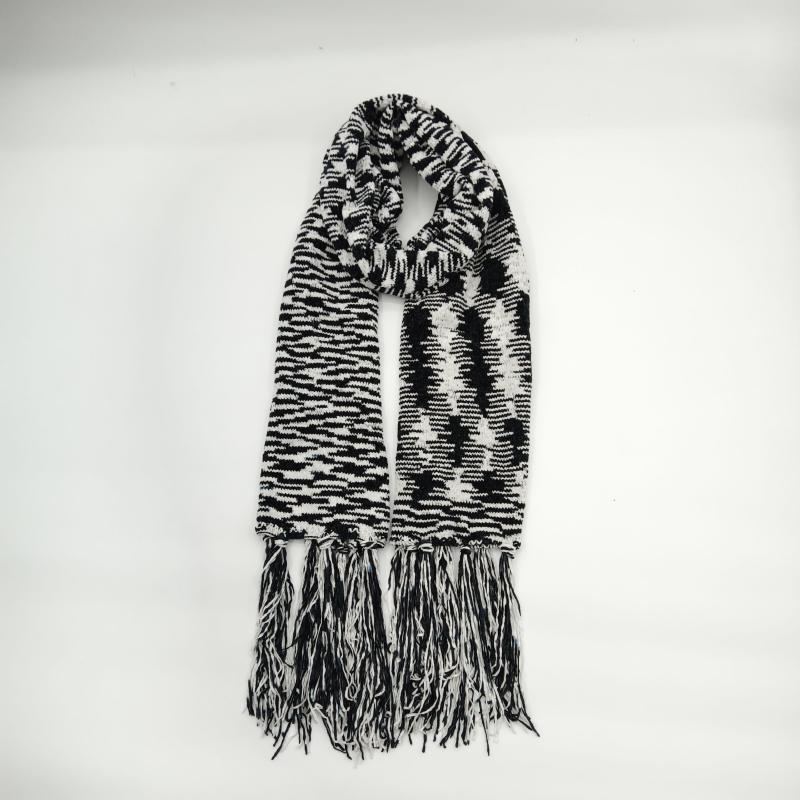 Black and white houndstooth patterned knit scarf with long mixed fringe tassels displayed folded on white background