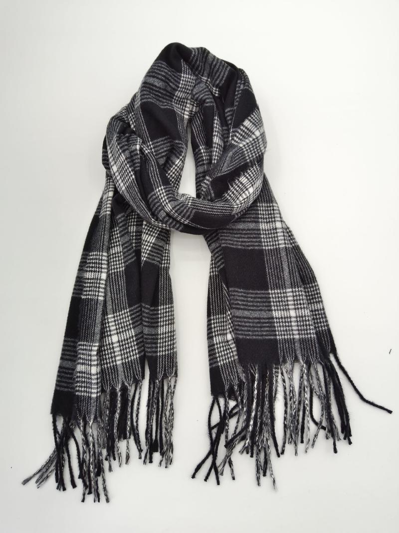 Black and white plaid tartan scarf with fringe ends, loosely knotted and laid flat on white background