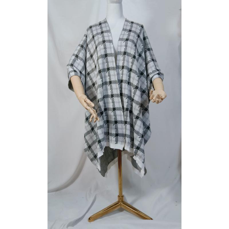 Black and white houndstooth plaid knit open-front poncho wrap cape draped on a mannequin with gold stand