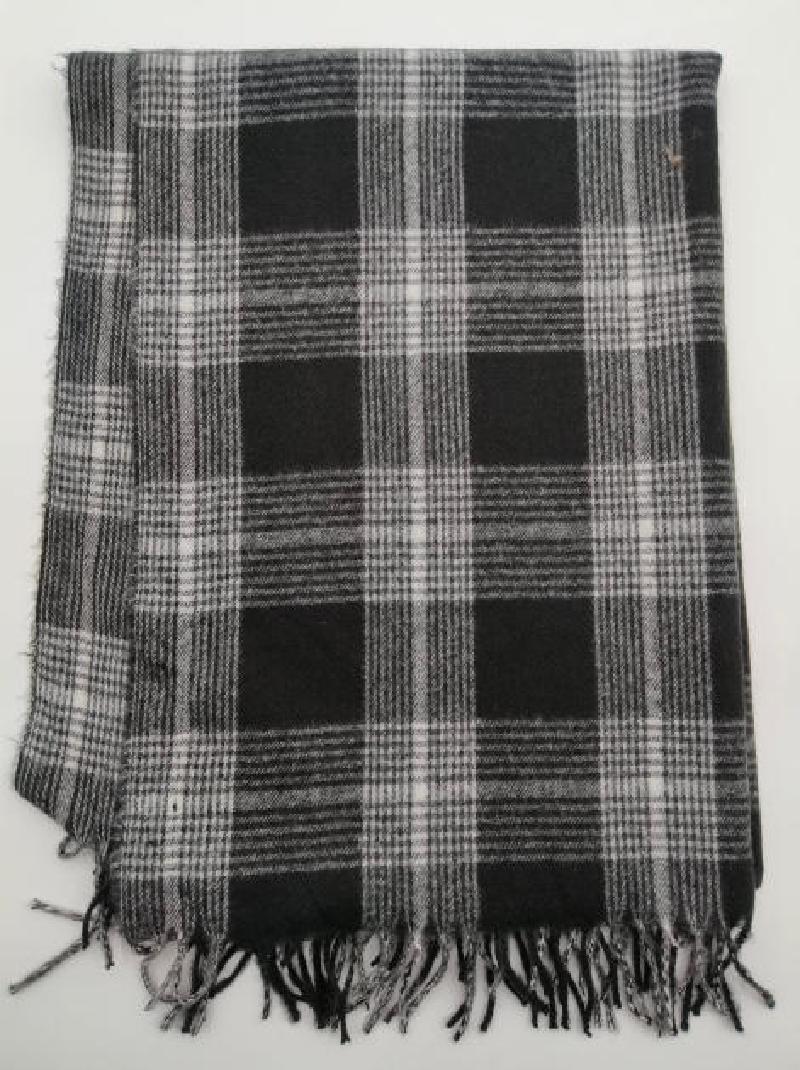 Folded black and white tartan plaid woven throw blanket with knotted fringe trim on white background