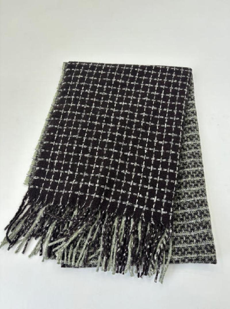 Folded black and white woven check pattern throw blanket with fringe trim, reversible houndstooth design