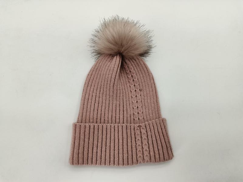 Blush pink ribbed knit winter beanie hat with large faux fur pom pom on white background