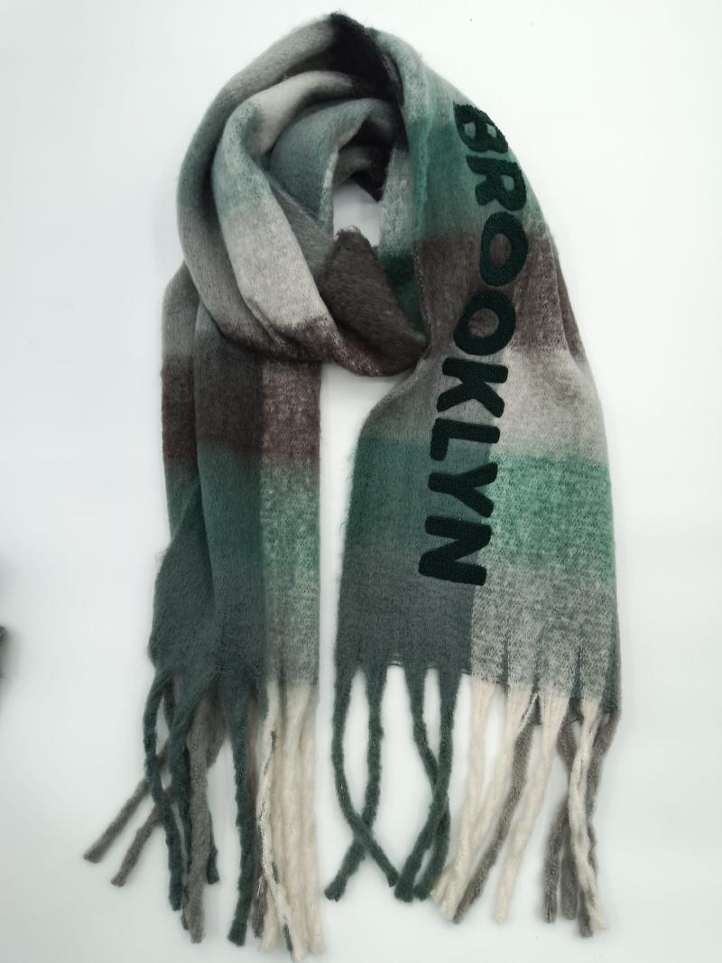 Folded Brooklyn-lettered plaid scarf in green, grey, and brown ombre pattern with twisted fringe ends on white background