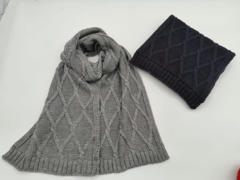 Grey cable knit diamond pattern scarf laid flat beside a folded navy blue cable knit scarf on white background