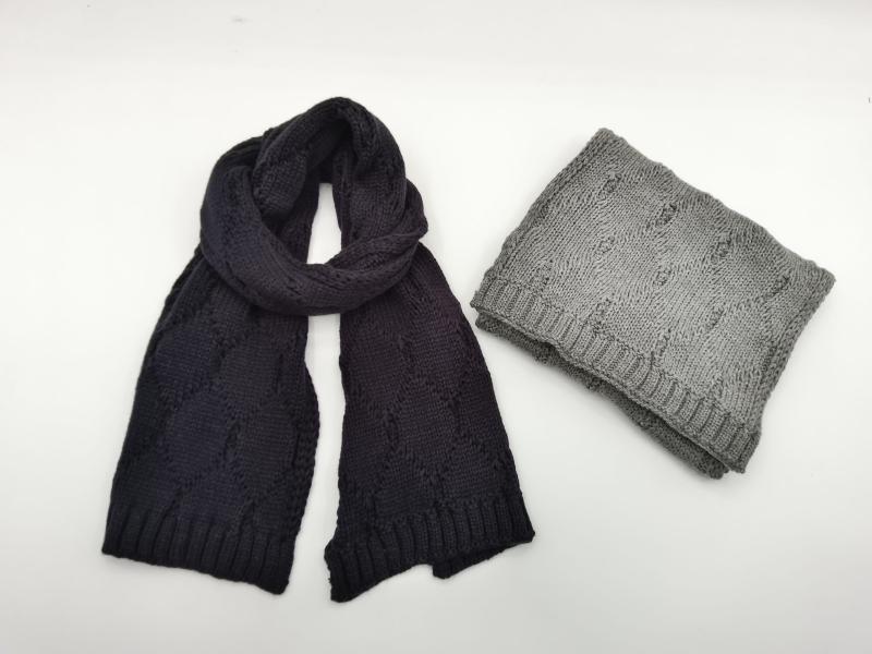 Two cable knit scarves displayed on white background: navy blue draped scarf and folded gray scarf with ribbed edges