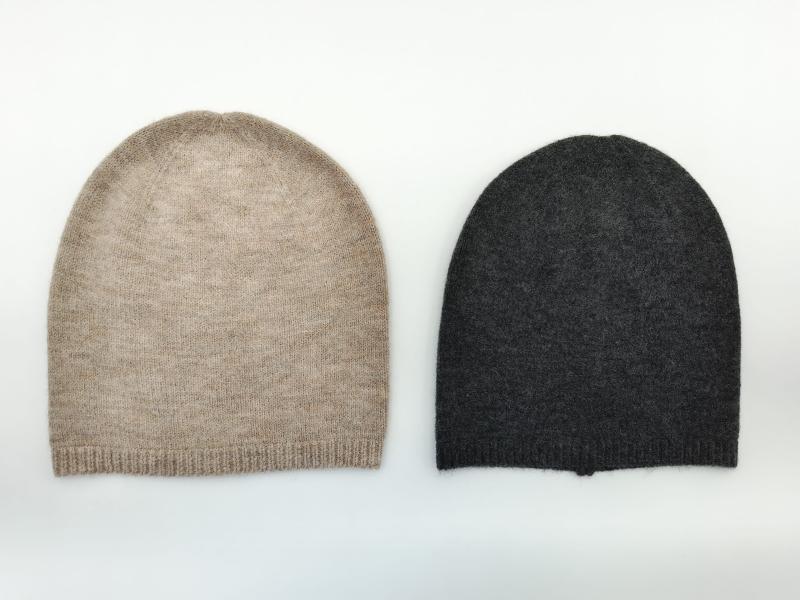 Two flat-lay cashmere slouchy beanies side by side, oatmeal beige and charcoal gray, ribbed cuff knit hats on white background