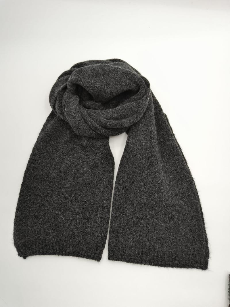 Dark charcoal grey knitted scarf loosely coiled and laid flat on white background showing two long ends