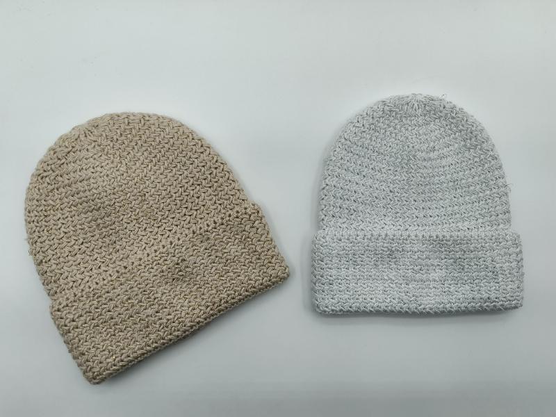 Two chunky knit beanie hats side by side, one beige without cuff and one light gray with folded cuff, on white background