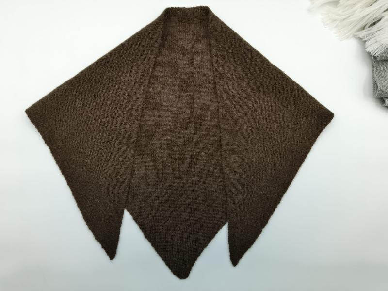 Dark brown hand-knitted triangular shawl with three pointed panels laid flat on white surface
