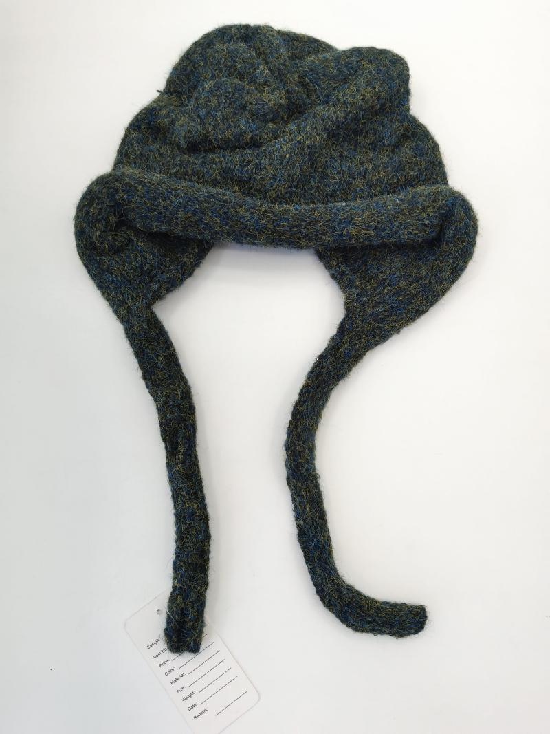 Chunky knit blue-green marl wool earflap winter hat with long braided ties laid flat on white background with product tag