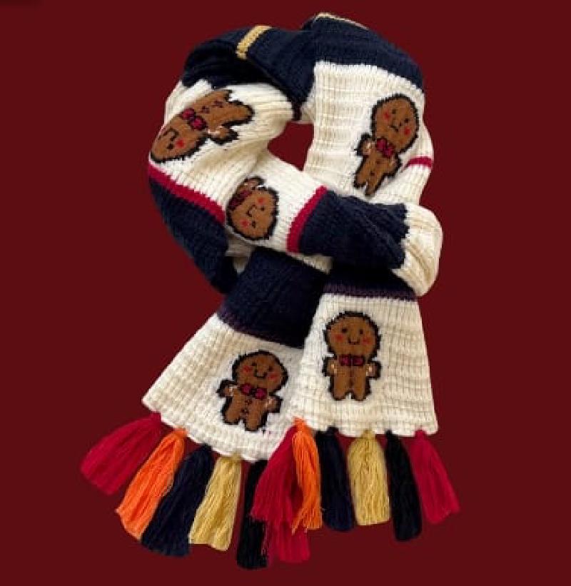 Cream and navy chunky knit scarf with gingerbread man pattern and multicolor fringe tassels on dark red background