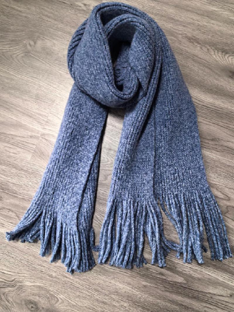 Long chunky knit grey marl winter scarf with tassel fringe ends, folded on wooden floor