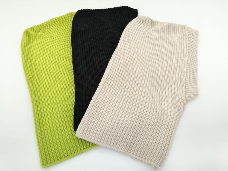 Three folded chunky ribbed knit sleeveless vest tops in lime green, black, and beige laid on white background
