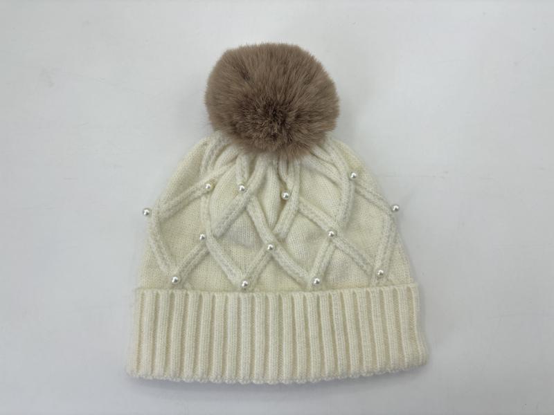 Cream cable knit winter beanie with pearl bead accents, ribbed cuff, and large taupe faux fur pom-pom on top