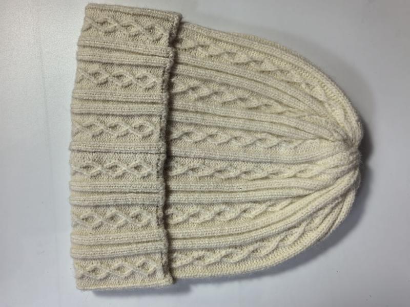 Cream ivory cable knit wool beanie hat laid flat showing folded cuff and textured diamond pattern stitching