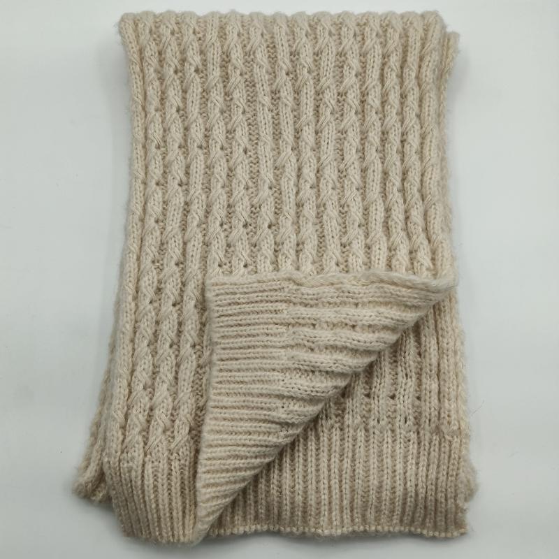 Folded cream chunky cable knit throw blanket showing ribbed texture and reverse side on white background