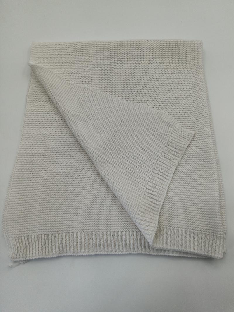 Folded cream chunky knit cotton throw blanket with ribbed edges, showing textured weave pattern on white background