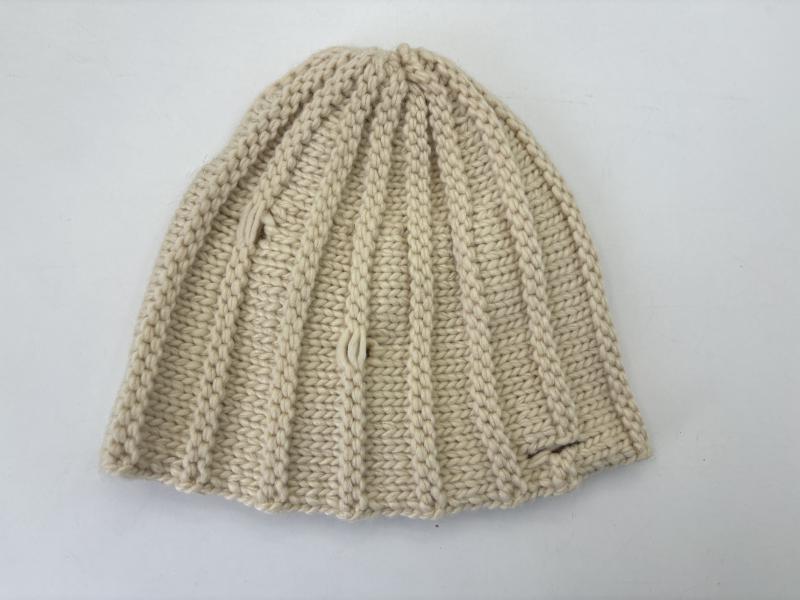 Flat lay of a cream chunky ribbed knit beanie hat in ivory natural yarn, folded to show textured stitch pattern