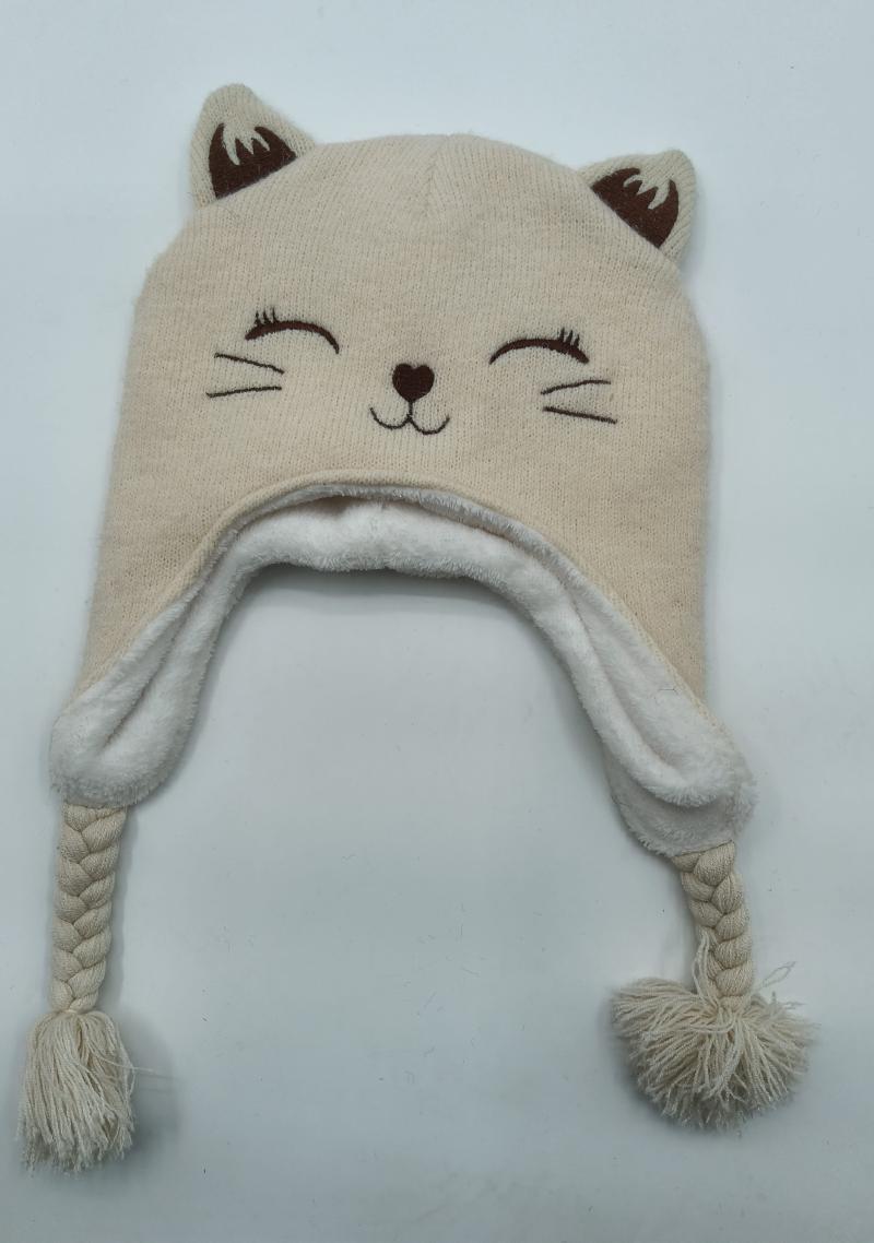 Cream knitted cat face winter hat with ear flaps, braided ties, pom poms, fleece lining, and embroidered cat features