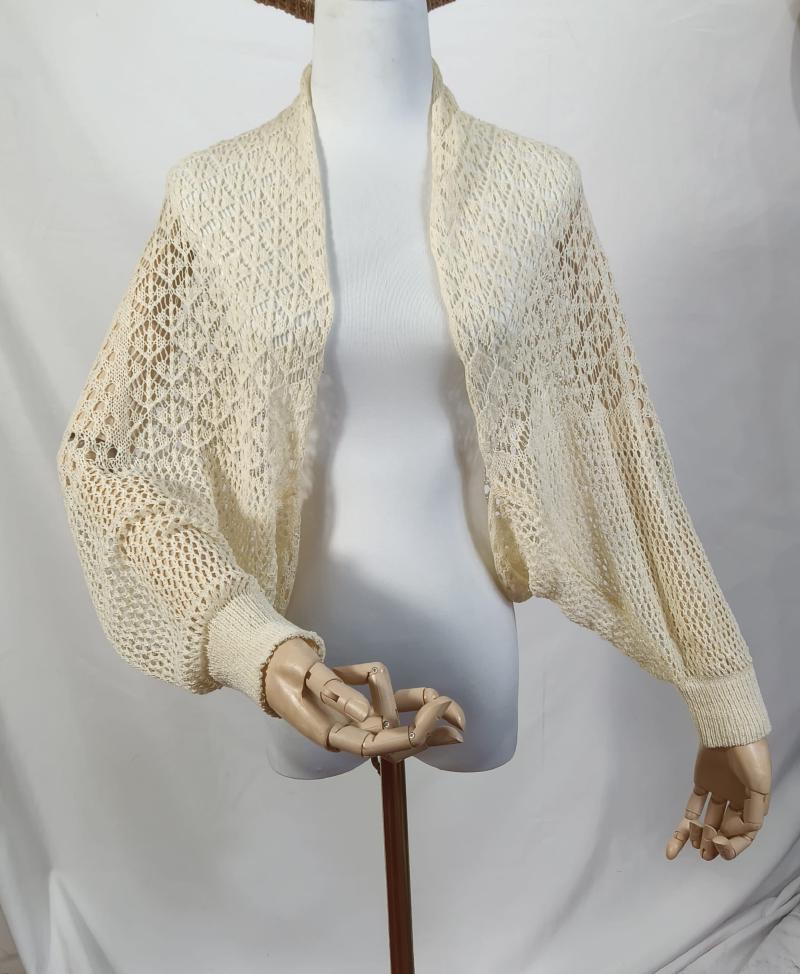 Cream ivory open-knit crochet bolero shrug with balloon bishop sleeves and ribbed cuffs on a mannequin
