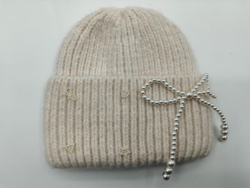 Cream ribbed knit winter beanie hat with decorative pearl bow and small rhinestone motifs on the cuff