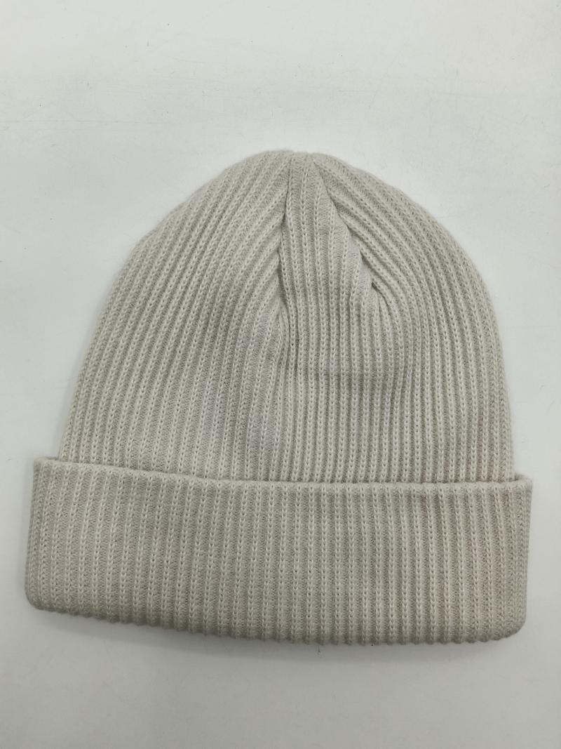 Cream ribbed knit cuffed beanie hat laid flat on white background, showing fine rib texture and folded brim