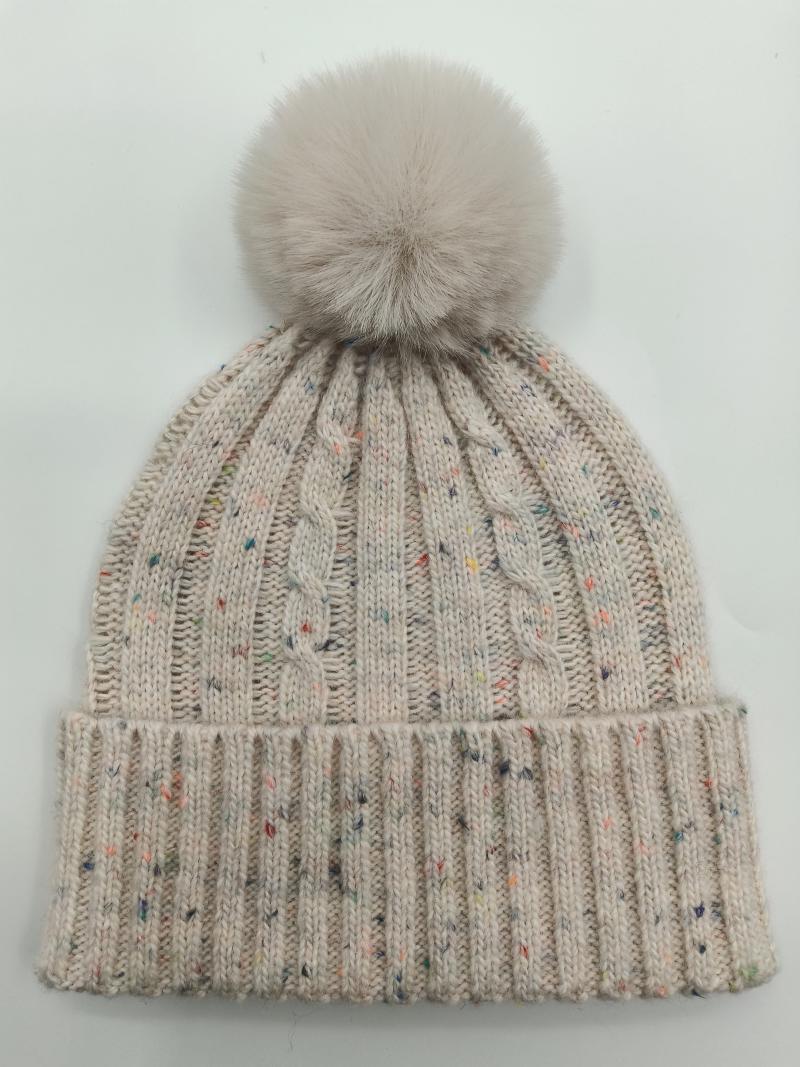 Cream cable knit winter beanie hat with multicolor fleck detailing and large fluffy faux fur pom pom on top