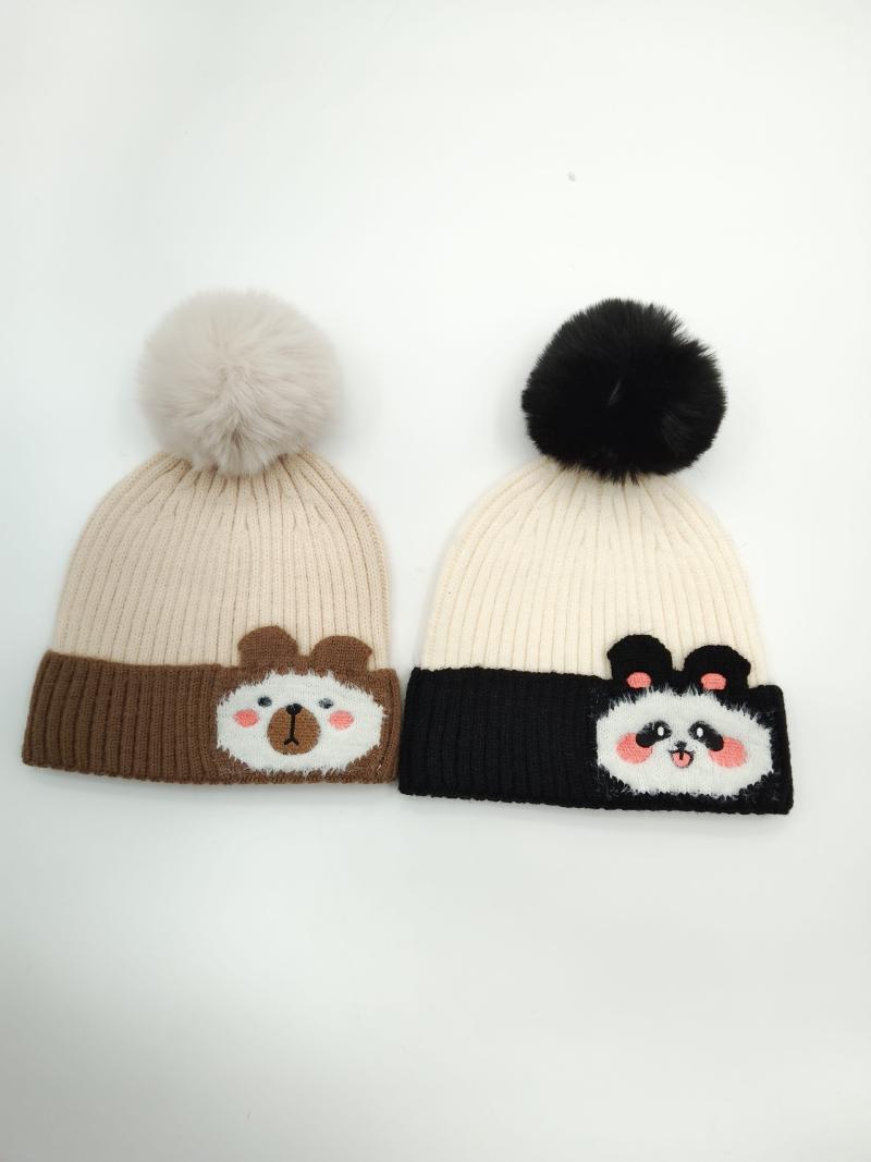 Two knit beanies with pom poms: brown bear design on tan hat and panda design on black and cream hat
