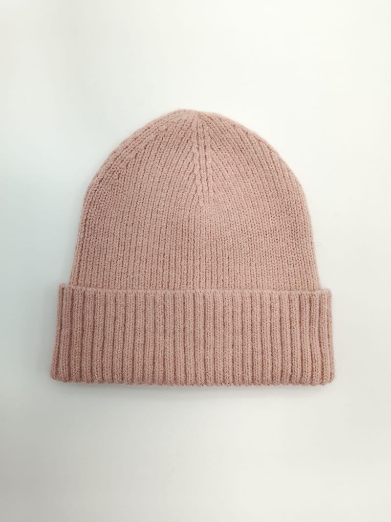 Flat lay of a dusty pink ribbed knit winter beanie hat with a wide folded cuff on a white background