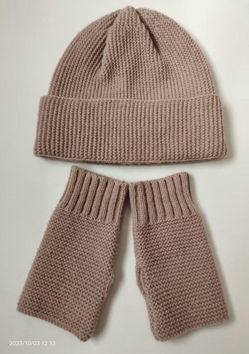 Handknit dusty pink ribbed beanie hat and matching fingerless mittens set laid flat on white background