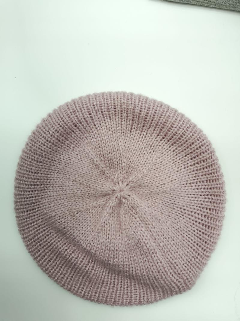 Top view of a dusty rose pink ribbed knit beret hat laid flat on a white surface, showing spiral crown detail