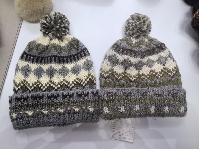 Two chunky knit Fair Isle pom pom beanies in grey, olive green and cream with folded cuff, displayed side by side
