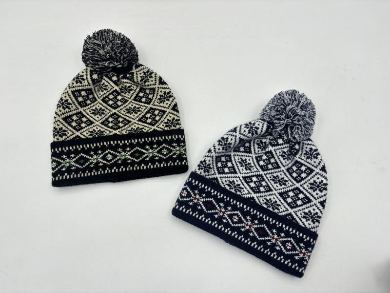 Two Fair Isle knit pom pom beanies in black-cream and navy-white Nordic snowflake pattern on white background