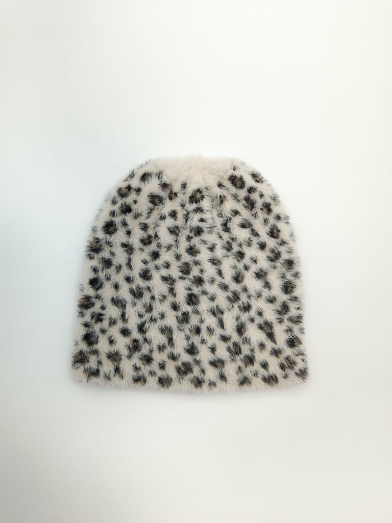 Flat lay of a fluffy ivory beanie hat with black and brown leopard spot print pattern on white background