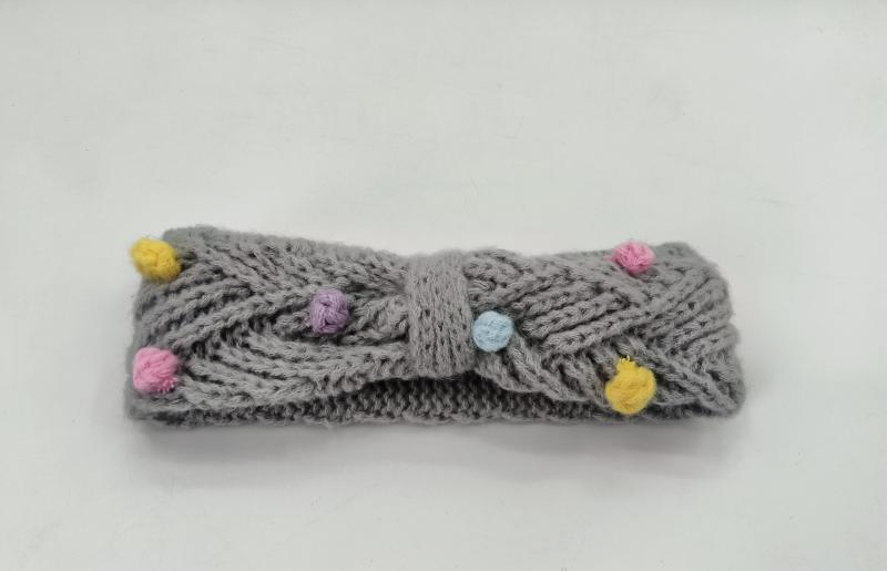 Gray cable knit headband with multicolor pom poms in yellow, pink, purple and blue, twisted bow center detail