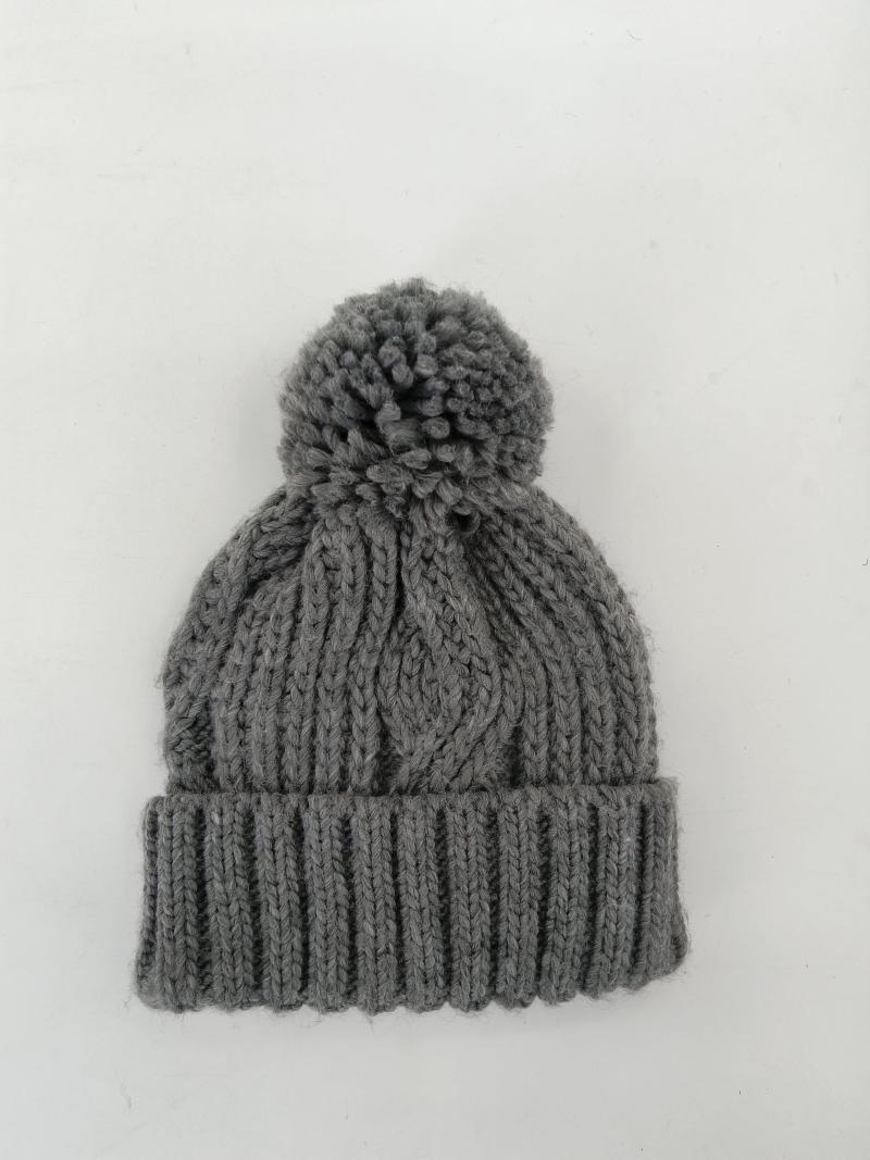 Grey chunky cable knit winter beanie hat with large pom pom and ribbed cuff, flat lay on white background