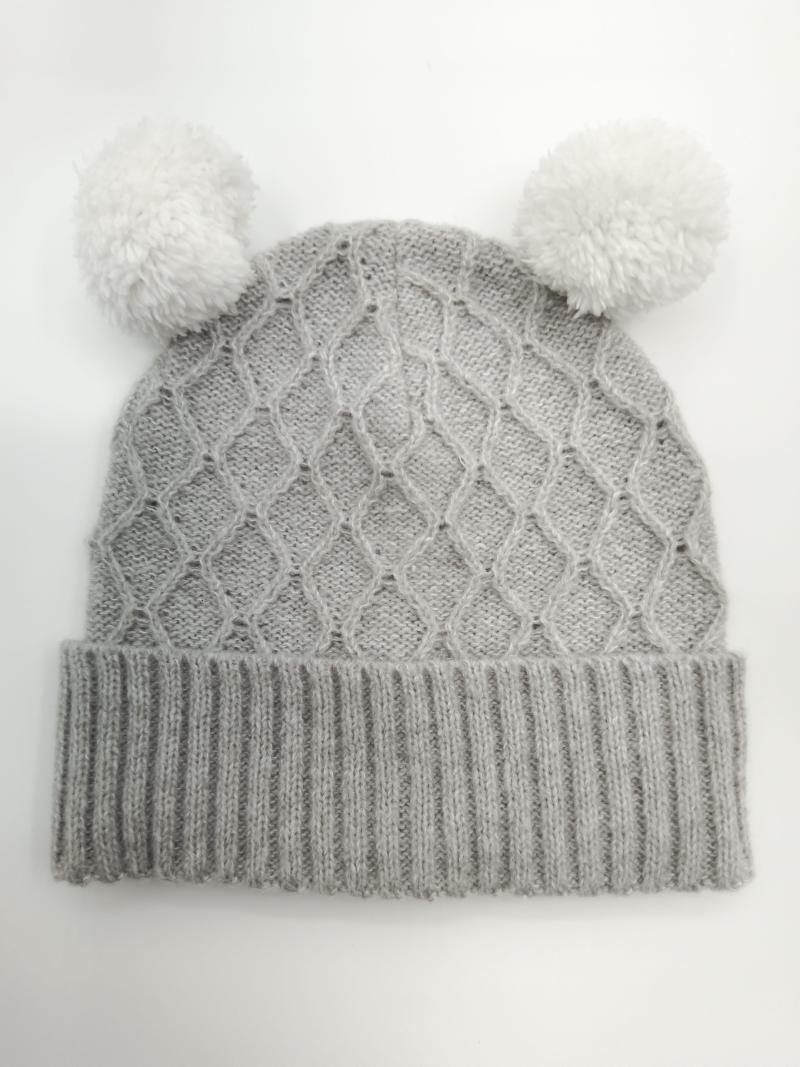Grey cable knit winter beanie hat with two white fluffy pom poms on top, ribbed cuff, laid flat on white background