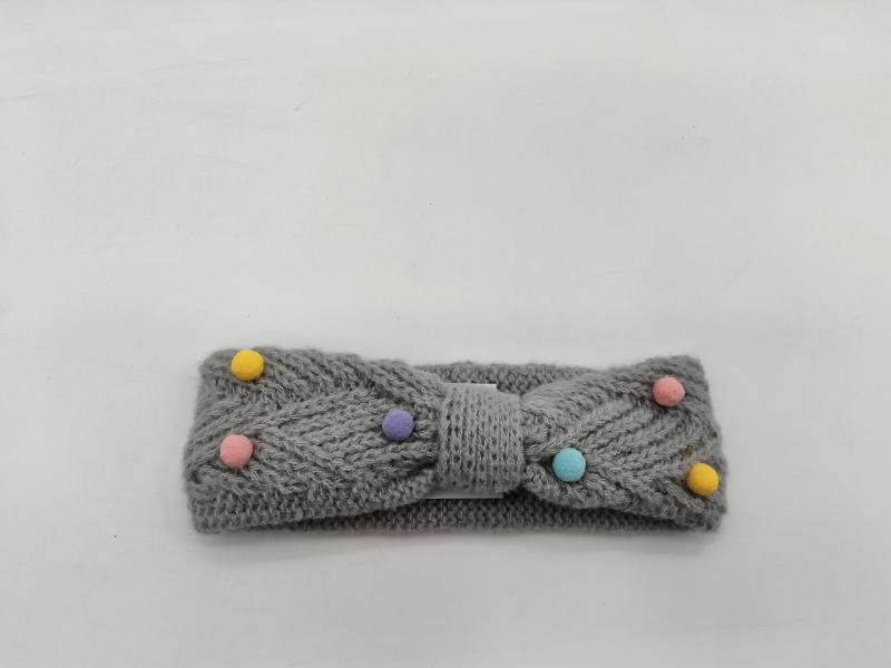 Grey knitted bow headband with multicolor pastel pom poms in yellow, pink, purple, teal on white background