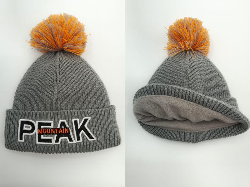 Grey chunky knit winter beanie with orange pom-pom, embroidered block letter patch, and soft fleece inner lining shown front and interior views