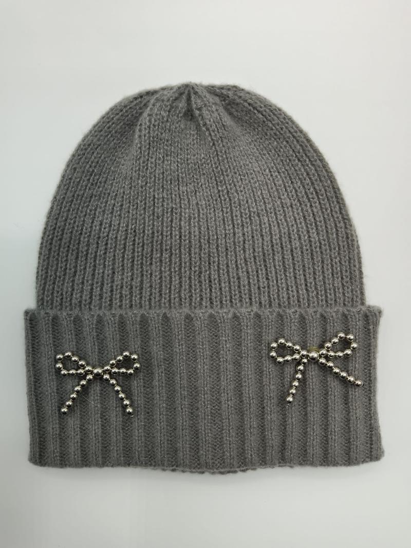 Grey ribbed knit winter beanie hat with two silver beaded bow brooches on folded cuff, flat lay on white background