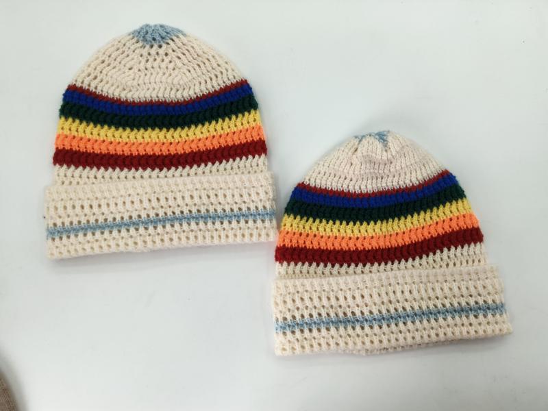 Two handmade cream crochet beanies with rainbow stripes in blue, green, yellow, orange, red on white background