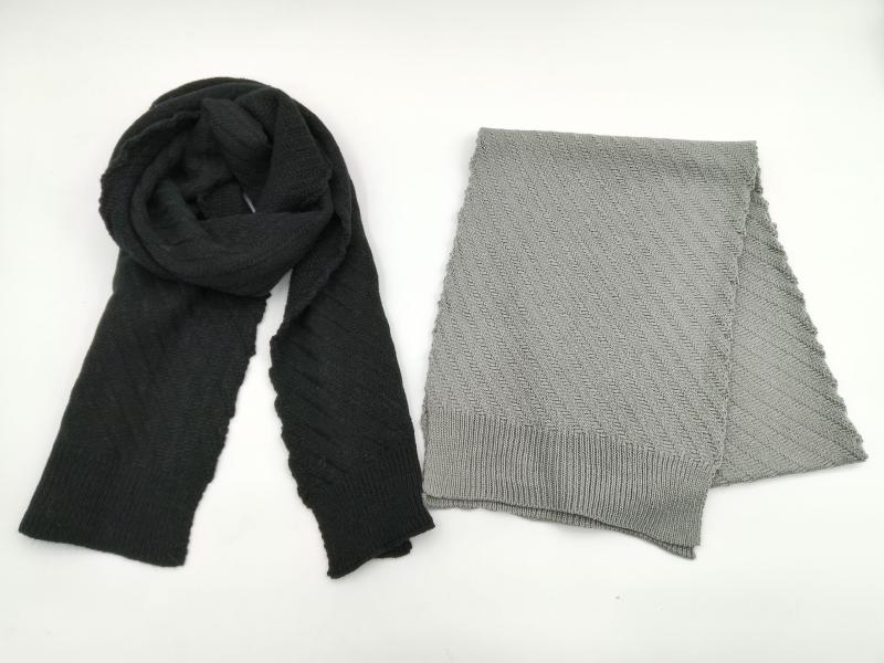 Two knit scarves flat lay: black draped scarf and folded light grey herringbone pattern scarf with ribbed edges on white background
