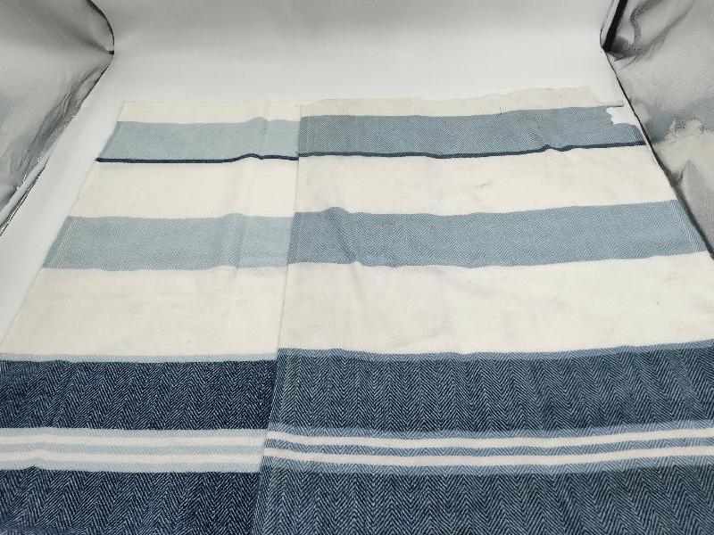 Flat lay of a herringbone weave cotton throw blanket with navy blue, light blue, and white horizontal stripes